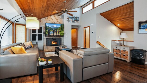 A modern living room with a fireplace, leather sofas, a dining table, and a stone accent wall. - 20 Lassen Lane-Sunriver, Oregon: Hot Tub, BBQ, WiFi, SHARC Aquatics, Tubing Hill, Mt. Bachelor, Golf, Deschutes River, Tennis, Bike Paths (Bend)
