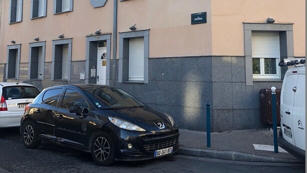 En byggnad med flera fönster och en parkerad bil framför.