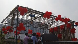 An outdoor seating area with a pergola covered in red heart-shaped decorations, a few chairs, and a table with people seated. - 5 minutes to the JAY PRABHA MEDANTA HOSPITAL  ! Family-sized room (Patna)