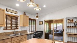Une cuisine dotée de plans de travail en granit, de meubles en bois, d’un lave-vaisselle encastré et d’un coin repas avec une table et des chaises.