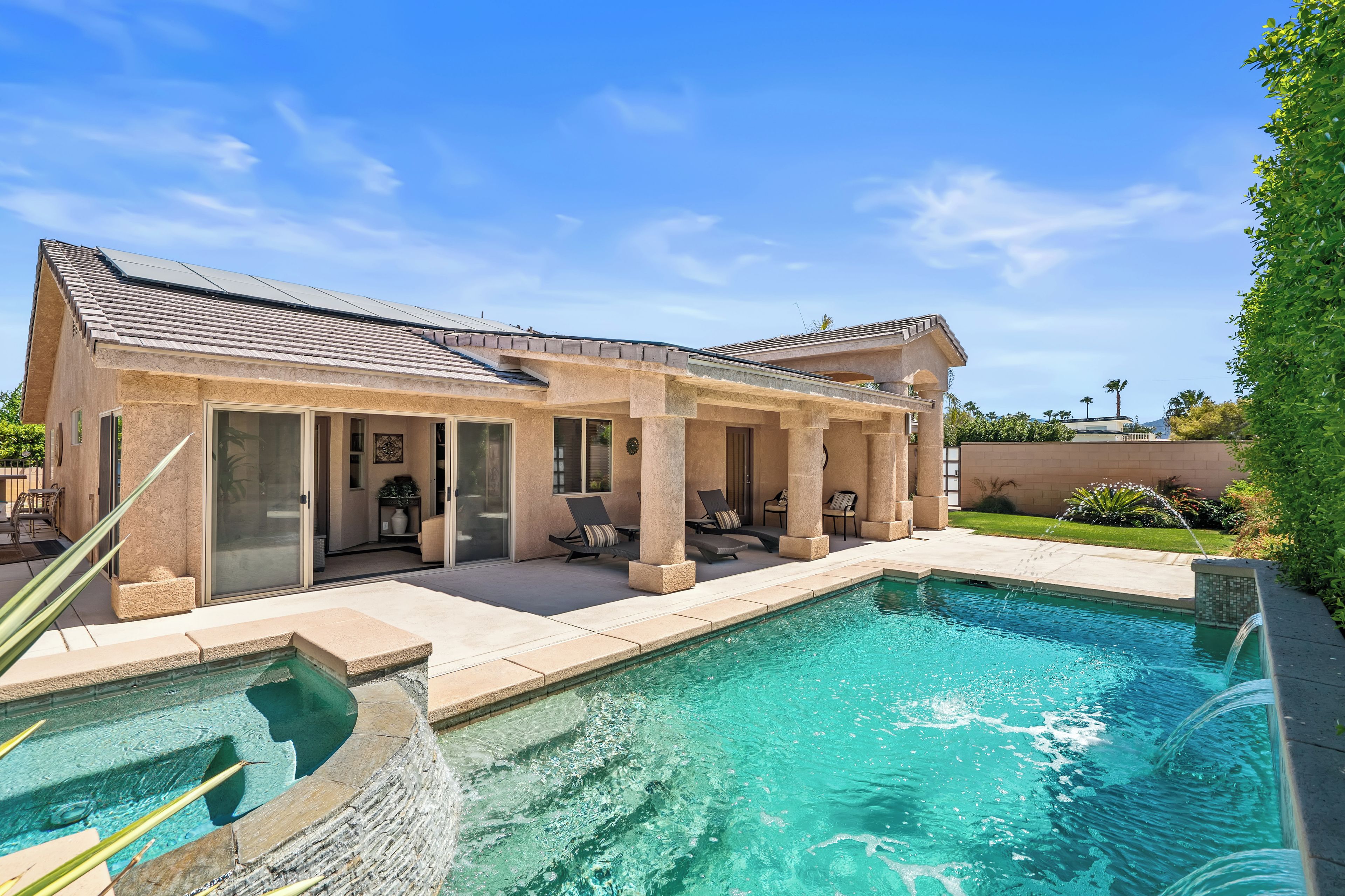 A house with a swimming pool, outdoor seating, and a covered patio area.