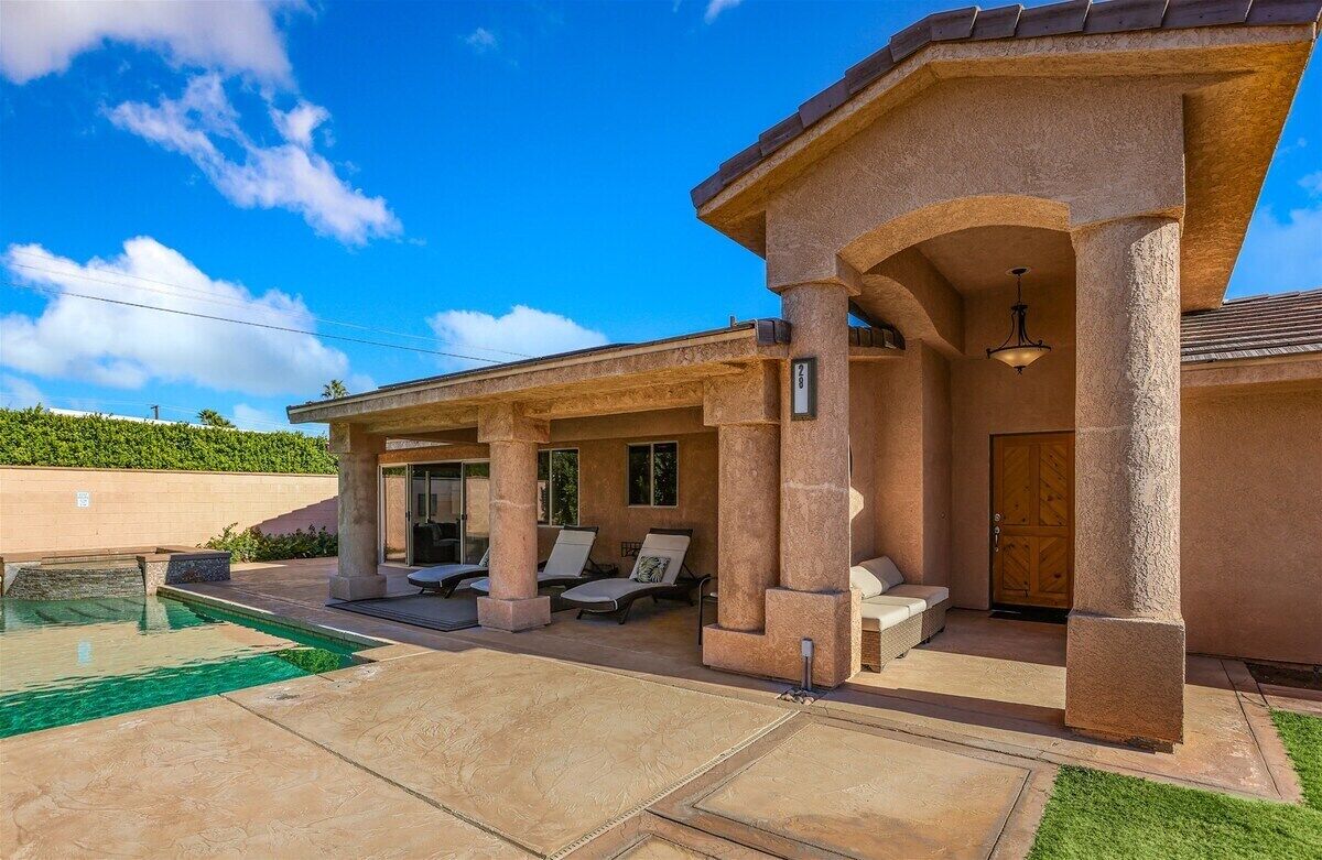 A house with a pool, outdoor seating, and a covered patio area.