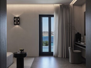 Een moderne badkamer met uitzicht op zee, een rond wastafel, een stoel en een spiegel.