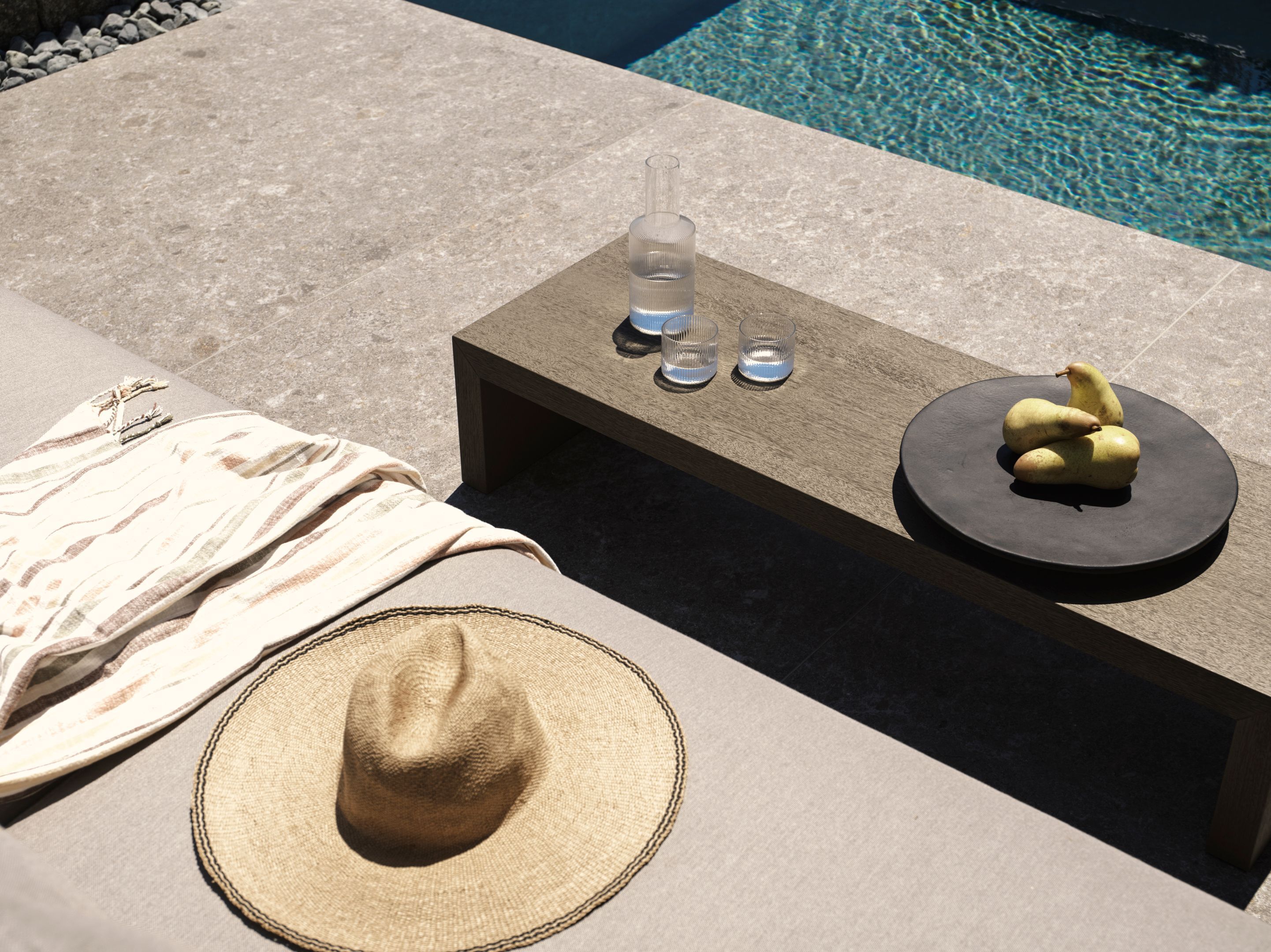 A poolside area with a table, a hat, and a towel.