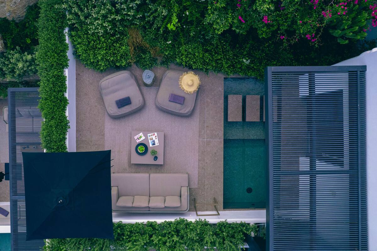 Eine Vogelperspektive zeigt eine Dachterrasse mit Sitzgelegenheit, einem kleinen Tisch und einem Pool.