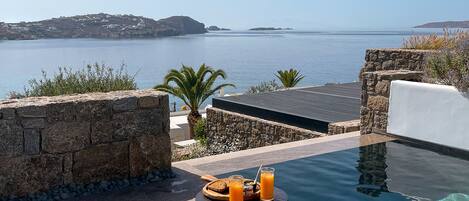An outdoor dining area with a pool and a view of the sea.