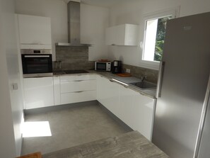 A modern kitchen with white cabinets, stainless steel appliances, and a window providing natural light. - LARGE VILLA (12 people) WITH A SWIMMING POOL, 5 MINUTES FROM THE BEACH (Six-Fours-les-Plages)