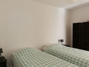 A bedroom with two beds, a nightstand with a lamp, and a black wardrobe. - LARGE VILLA (12 people) WITH A SWIMMING POOL, 5 MINUTES FROM THE BEACH (Six-Fours-les-Plages)