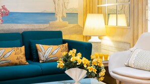 Ein Wohnzimmer mit einem blauen Sofa, einem weißen Sessel, einer Lampe, einem Couchtisch und einem Gemälde einer Statue.
