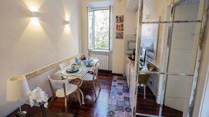 Uma sala de jantar com uma mesa posta para quatro pessoas, uma janela com vista e uma cozinha com frigorífico e micro-ondas.