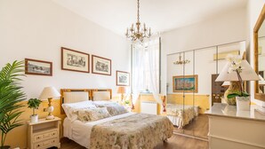 Une chambre à coucher avec un lit, des tables de chevet, un miroir et des tableaux encadrés accrochés au mur.