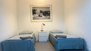 Una camera da letto con due letti singoli, un comodino, una lampada e un quadro appeso al muro.