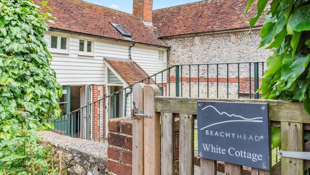 A wooden gate with a sign reading "BEACHYHEAD White Cottage".