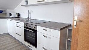 A modern kitchen with white cabinets, a stainless steel sink, and a built-in oven. - Modern studio for 4 people with a view of the mountains (Starigrad)