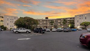 Un estacionamiento con varios coches y un edificio grande con un patio central.