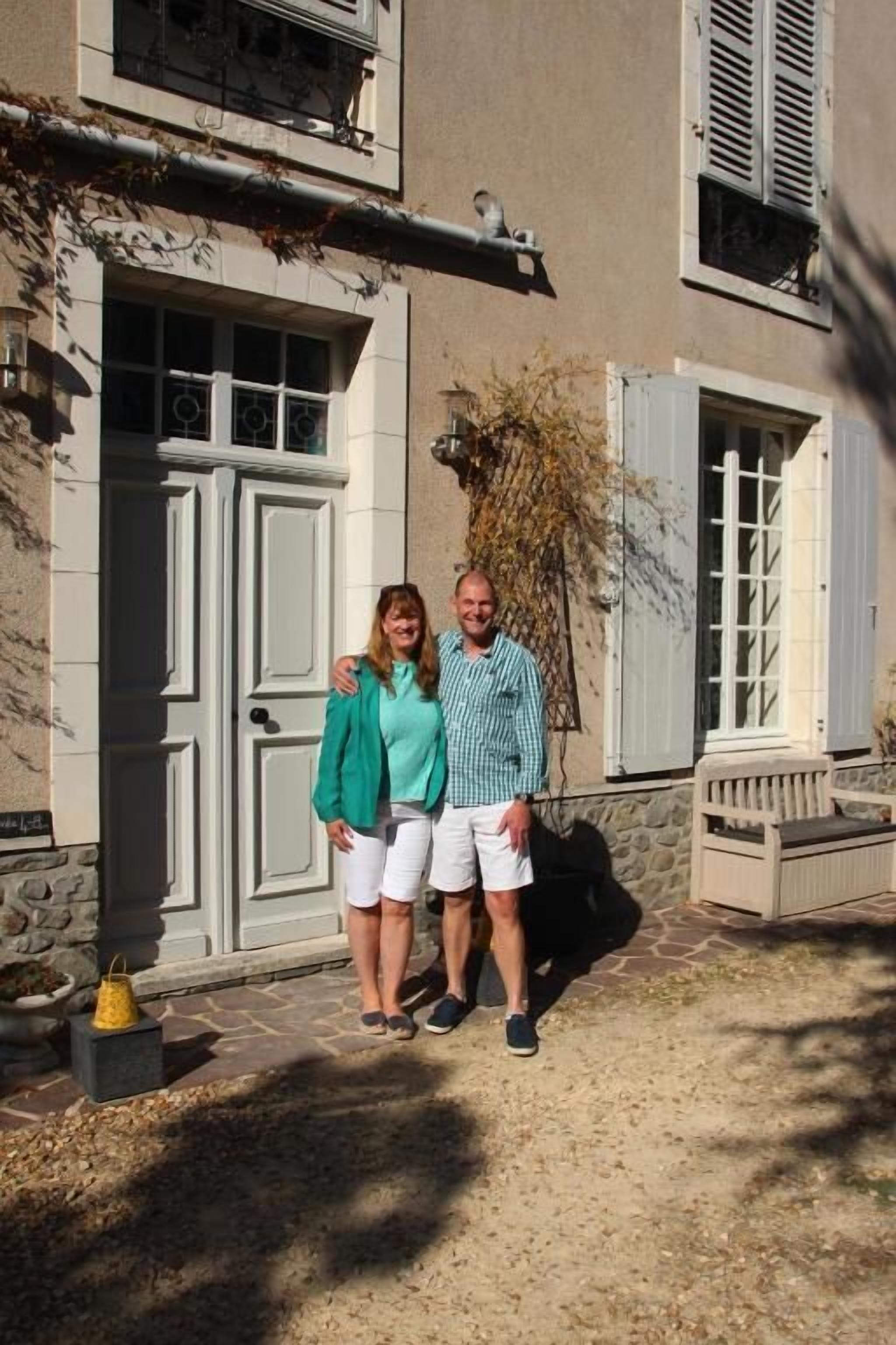 Un edificio con fachada de piedra, una puerta blanca grande y un pequeño porche con un banco.