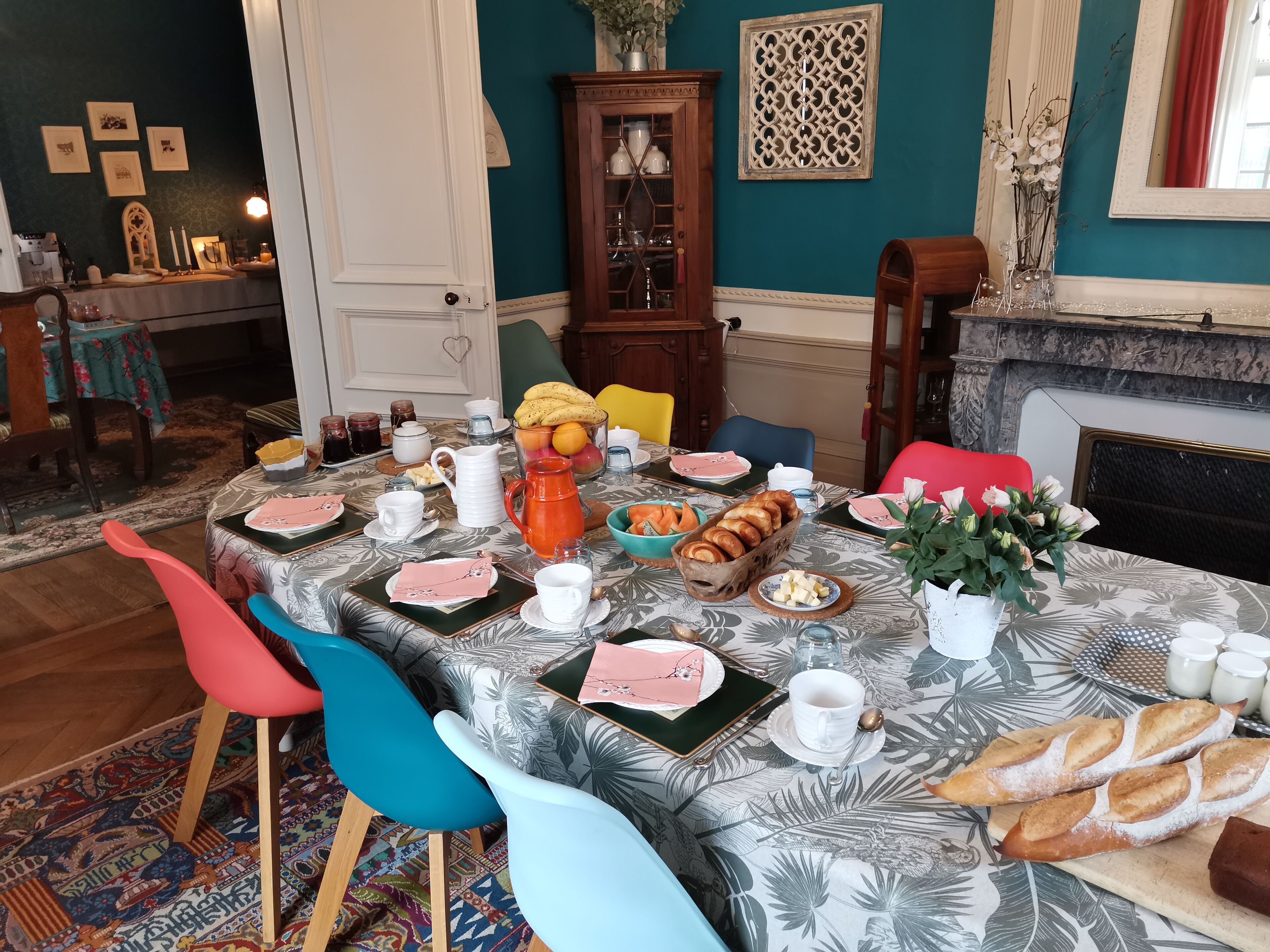 Ein Esszimmer mit Tisch, gedeckt für ein Frühstück, mit Brot, Früchten und verschiedenen Speisen.