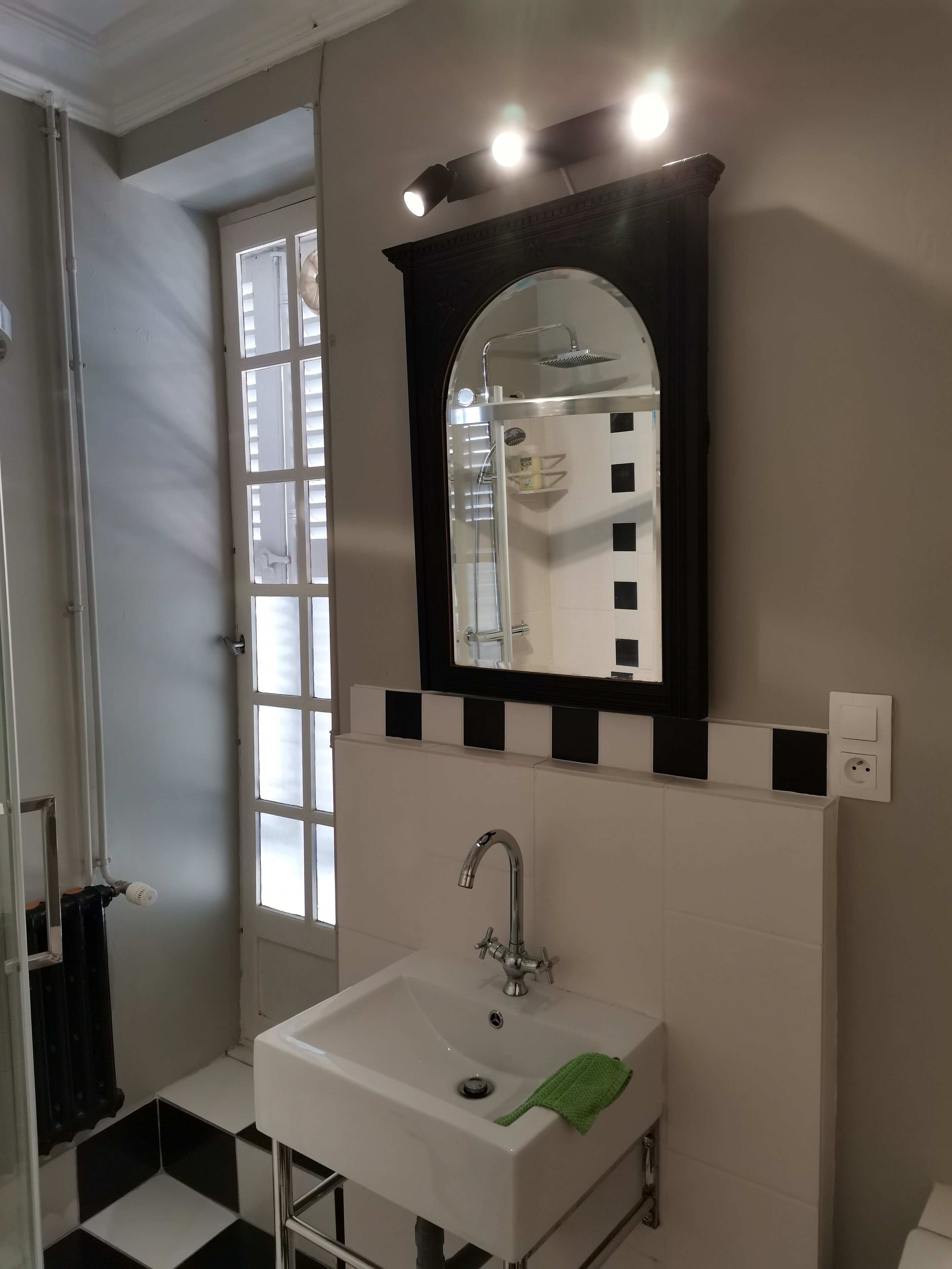 A bathroom with a white sink, a mirror with a black frame, and a shower area.