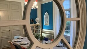 A dining area with a table set for four, a chandelier, and a window with a decorative frame. - 5 Grande Rue (Le Lude)