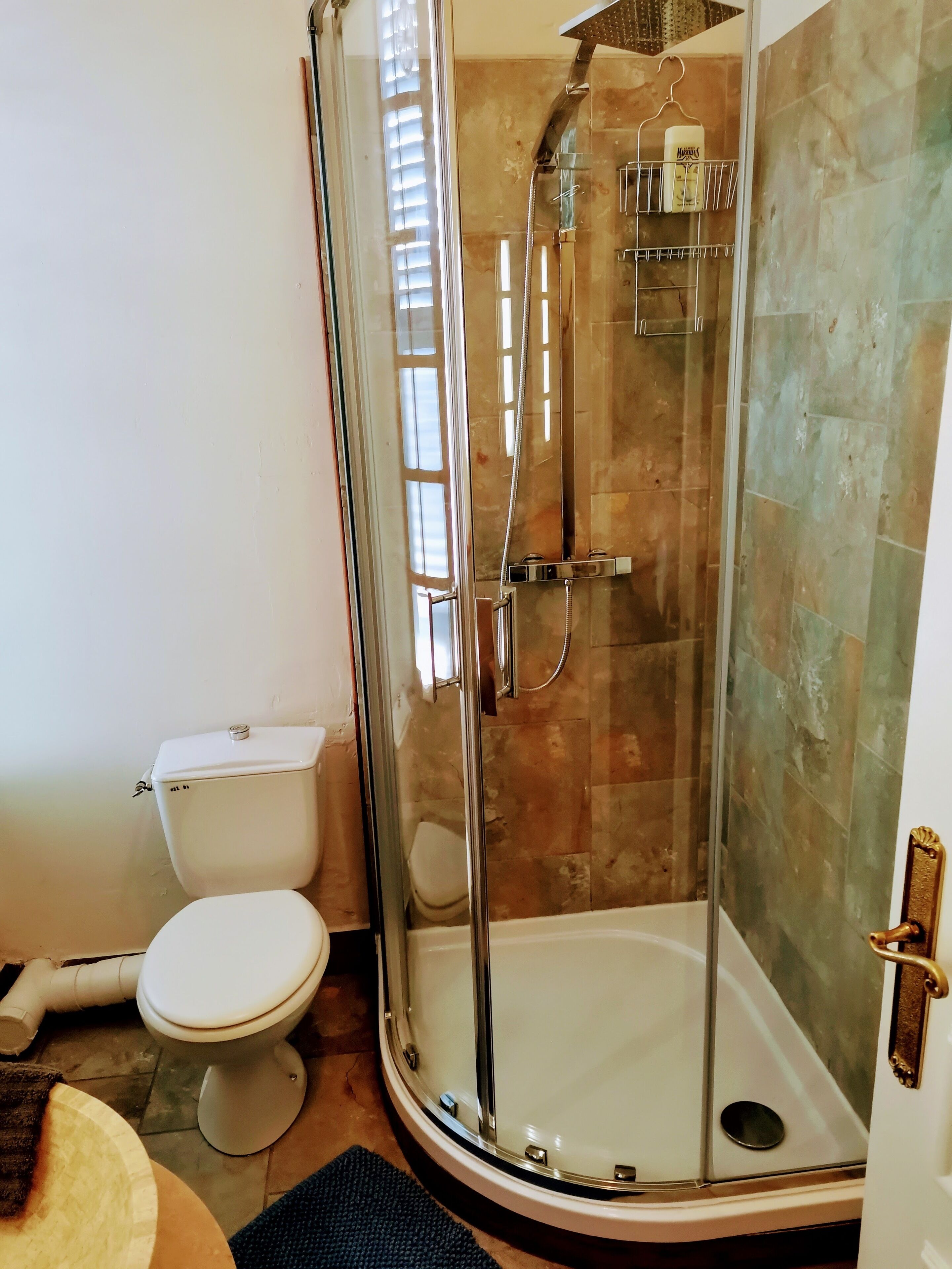 A modern bathroom with a glass-enclosed shower, a toilet, and a sink.