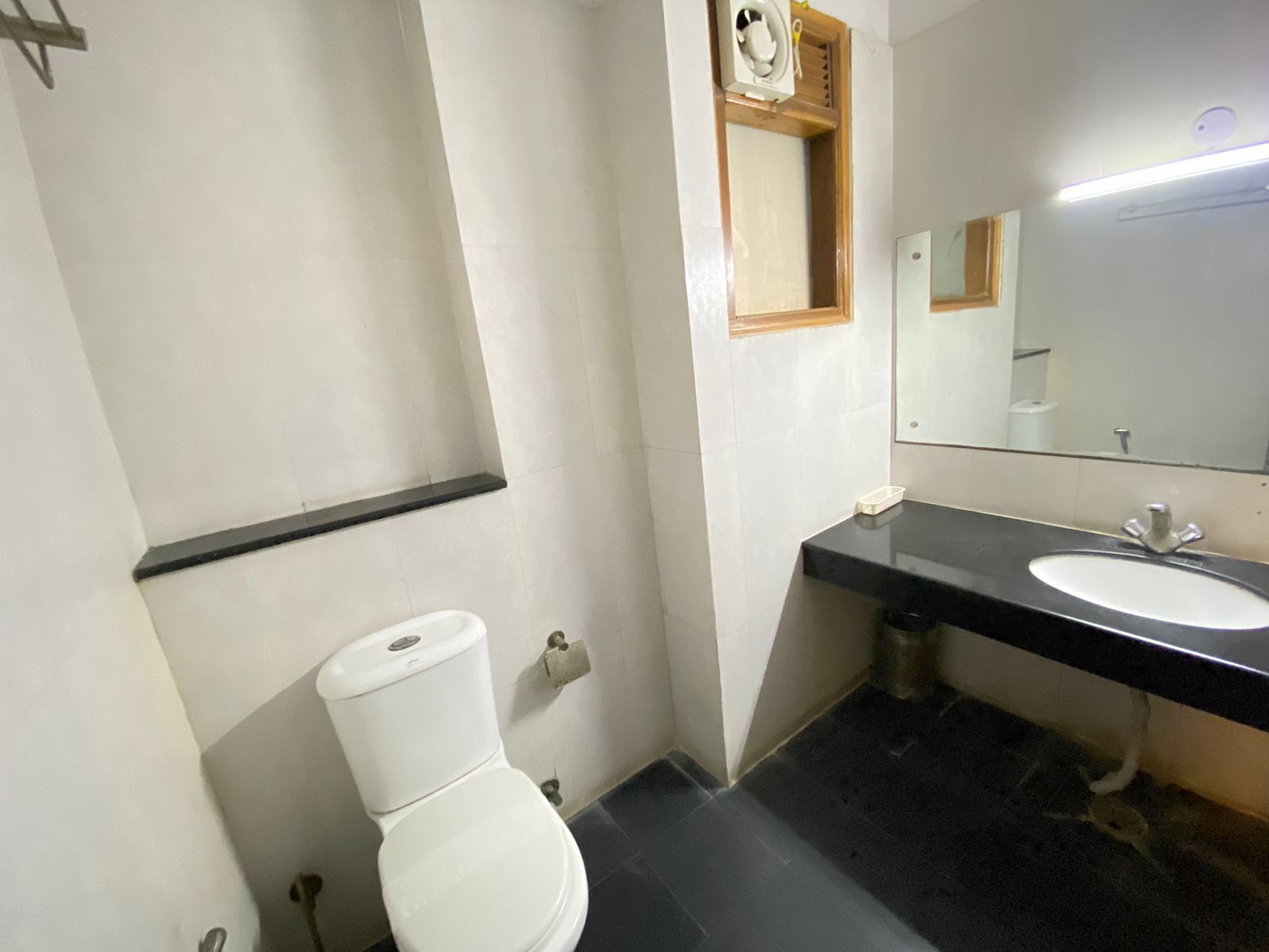 A bathroom with a white toilet, a black sink, and a mirror above the sink.