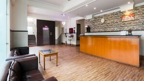 A hotel lobby with a reception desk, a staircase, leather seating, and a wooden floor. - Imperial Hotel Noida (Noida)