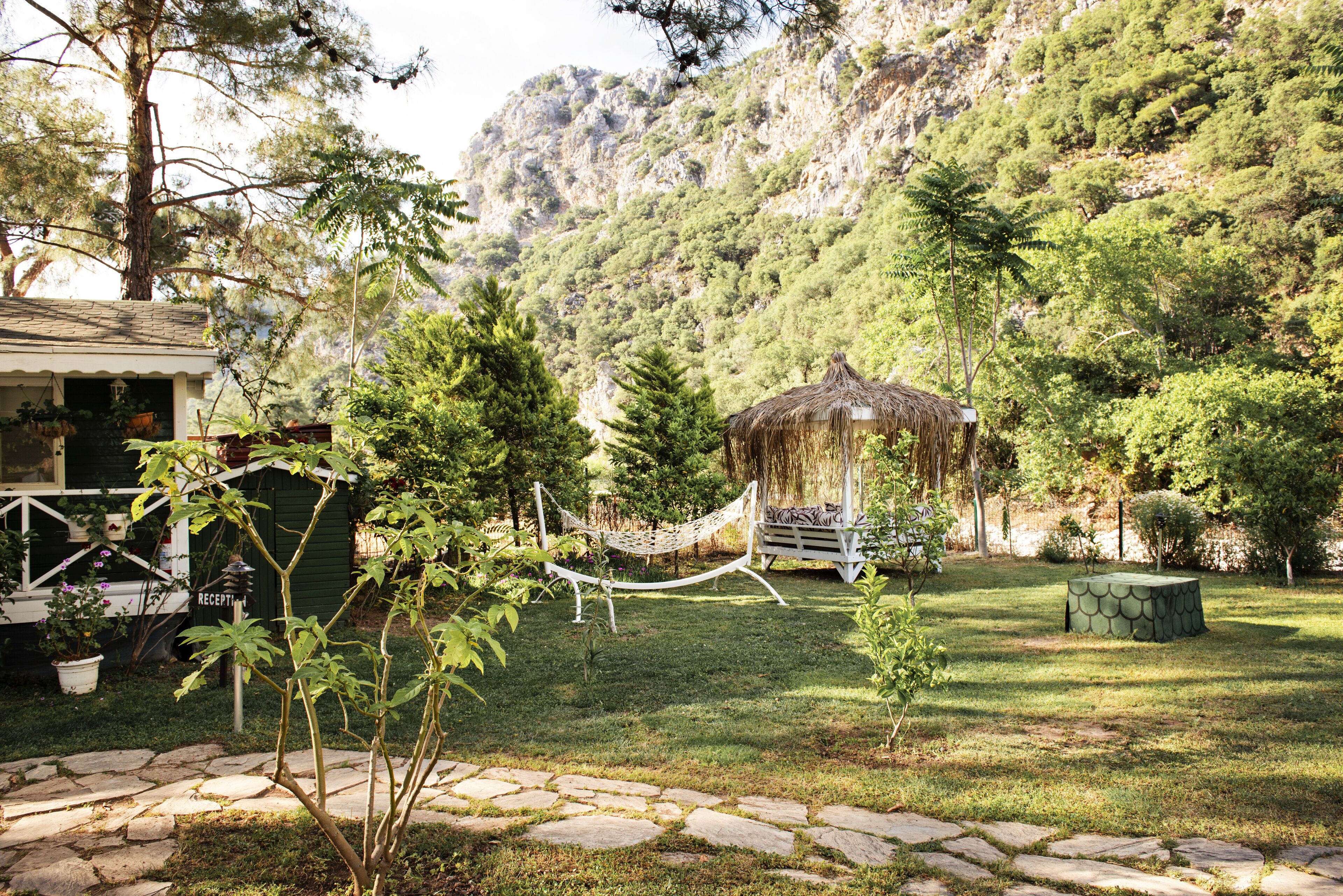 A garden with a hammock, a gazebo, and a stone pathway.