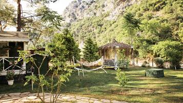 A garden with a hammock, a gazebo, and a stone pathway.
