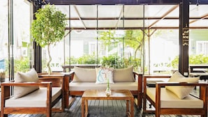 A covered outdoor seating area with wooden furniture, a hanging plant, and a view of the surrounding greenery. - Lukkies Lodge (Kemer)