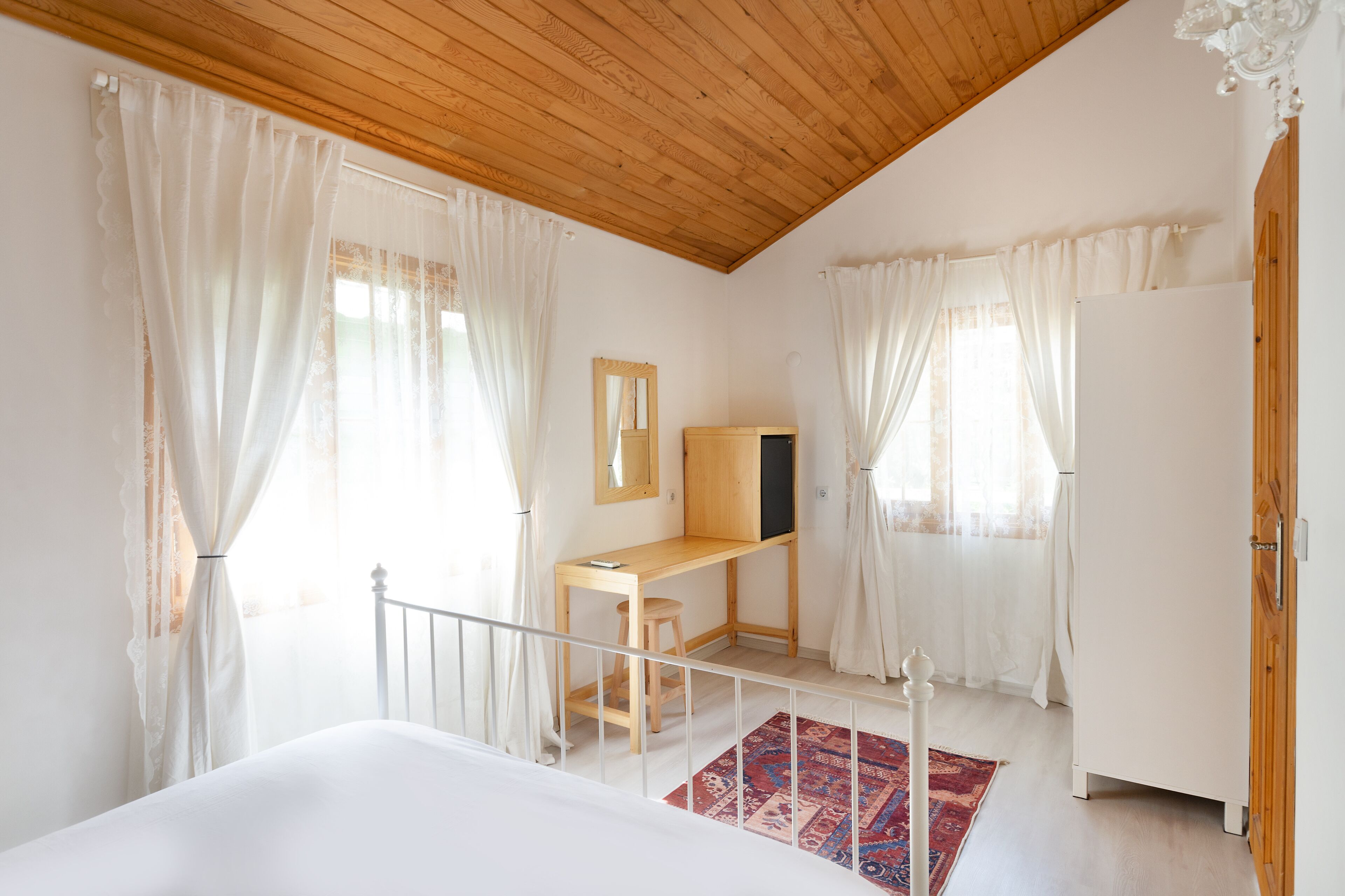 A bedroom with a wooden desk, a bed, a mirror, and a wardrobe.