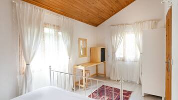 A bedroom with a wooden desk, a bed, a mirror, and a wardrobe.