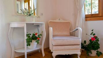 Ein Zimmer mit einem weißen Schminktisch, einem weißen Stuhl und zwei Blumentöpfen mit Blumen.
