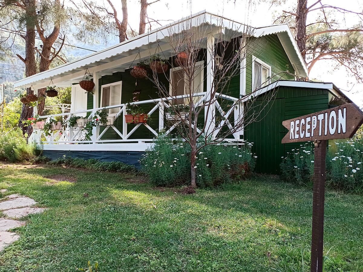 A green house with a white porch and a sign that reads "RECEPTION".