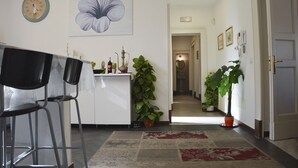 A modern kitchen with a dining area, featuring a clock, a large flower painting, and potted plants. - CASA GRANDE ALCALA HISTORIC CENTER (Catania)