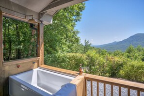 A wooden deck with a hot tub, a bottle, and two glasses. - Big View, Fire Pit, Cozy and Romantic - Writer's Block by Carolina Properties (Saluda)