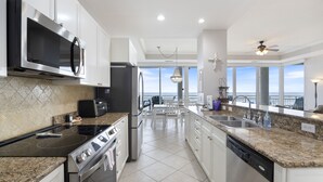 Una cocina moderna con electrodomésticos de acero inoxidable, encimeras de granito y vistas al océano a través de amplios ventanales.