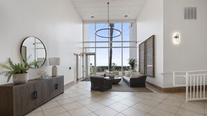 Un salón amplio con diseño moderno, que cuenta con un gran ventanal, una araña y una zona de estar confortable.