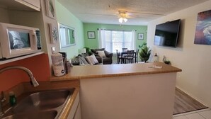 A compact kitchen with a central island, a dining area with a table and chairs, and a living space with a couch. - Private Beach Access Pool & Hot Tub Bbq Pits 1 Bedroom Home by RedAwning (South Padre Island)