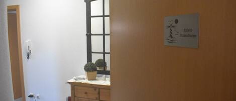 A hallway with a wooden door, a potted plant, and a sign reading "FEWO Strandturm".