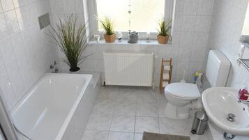 Bathtub, hair dryer, towels, toilet paper