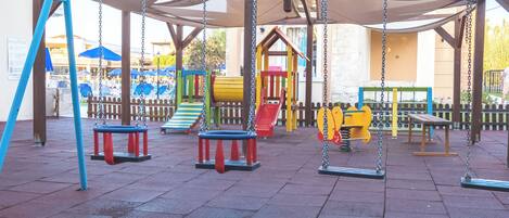 Un parque infantil con columpios y toboganes.
