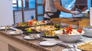Un buffet proposant une variété de plats, notamment des salades, des légumes et un grand saladier agrémenté d’une garniture décorative.