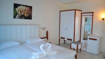 A hotel room with a bed, a wardrobe, a bedside table, a mirror, and a wall-mounted picture.