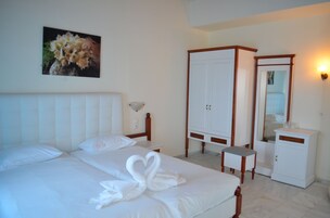 A hotel room with a bed, a wardrobe, a bedside table, a mirror, and a wall-mounted picture.