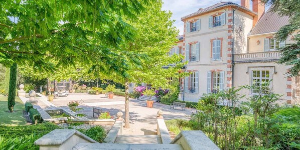 A courtyard with a fountain, benches, and a large tree.