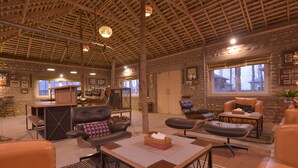 A spacious living area with a high wooden ceiling, leather furniture, and a stone wall. - Anand at the Satluj (Anandpur Sahib)