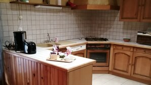 A kitchen with wooden cabinets, a tiled backsplash, and a central island with a toaster and coffee maker. - Gîte in the heart of a vineyard. (Razac-de-Saussignac)