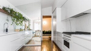 Una cocina moderna con armarios blancos, piso de madera y estufa integrada.