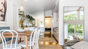 Una cocina amplia con una mesa de comedor de madera, sillas blancas y plantas colgantes.
