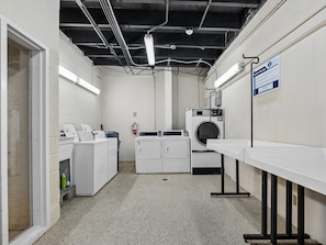 Een wasruimte met een wasmachine, droger en gestapelde wasmanden.